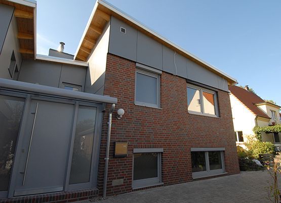 Ein Haus mit Ziegelfassade und Glastür, das eine einladende und moderne Atmosphäre ausstrahlt.