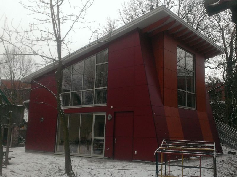 Rotes Haus mit einem schneebedeckten Garten, der eine ruhige Winterlandschaft darstellt.