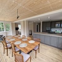 Ein Holztisch mit Stühlen, die um ihn herum angeordnet sind, in einem einladenden Raum.