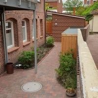 Ein Ziegelweg mit einer Bank und einem Feuerplatz, umgeben von einer einladenden Gartenlandschaft.