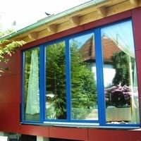 Ein rotes Haus mit einem blauen Fenster, das in einer klaren Umgebung steht.