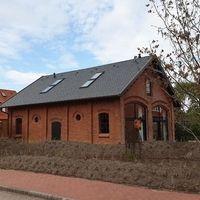 Ein Backsteinhaus mit einem Dach und Fenstern an der Seite, das eine einladende Atmosphäre ausstrahlt.