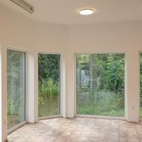 Ein heller Raum mit großen Fenstern und einem eleganten Holzboden, der eine einladende Atmosphäre schafft.