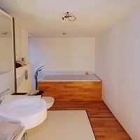 Badezimmer mit Holzboden und weißem Waschbecken, das eine moderne und einladende Atmosphäre schafft.