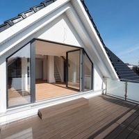 Dachterrasse mit Holzdeck und Glastüren, die einen modernen und einladenden Außenbereich schaffen.