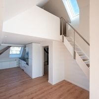Ein Loft mit Treppen und einer modernen Küche, die einladend und stilvoll gestaltet ist.