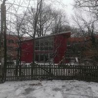 Ein rotes Haus im Schnee, umgeben von einem weißen Zaun, strahlt Ruhe und Gemütlichkeit aus.