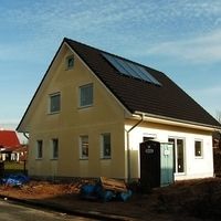Ein Haus mit Solarpanelen auf dem Dach, das umweltfreundliche Energie erzeugt und nachhaltiges Wohnen fördert.