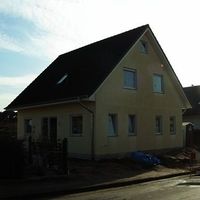 Ein Haus mit einem Dach und Fenstern an der Straßenseite, umgeben von einer ruhigen Umgebung.