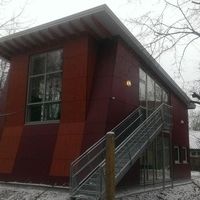 Ein rotes Haus mit einer Treppe, umgeben von Schnee, vermittelt eine winterliche und gemütliche Atmosphäre.