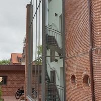 Ein Fahrrad steht vor einem Gebäude mit einer Glaswand geparkt.