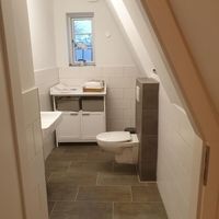 Badezimmer im Dachgeschoss mit Toilette, Waschbecken und Dusche, modern und funktional gestaltet.