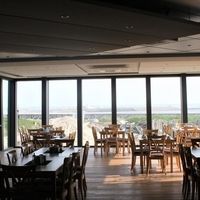 Ein Restaurant mit großen Fenstern, das einen Blick auf den Ozean bietet, schafft eine einladende Atmosphäre.