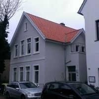 Ein Haus mit rotem Dach und weißen Wänden, umgeben von einer grünen Landschaft.