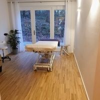 Ein Raum mit einem Tisch und Stühlen, der eine entspannende Atmosphäre für Behandlungen bietet.