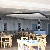 Ein Restaurant mit Holztischen und -stühlen, das eine gemütliche und einladende Atmosphäre bietet.